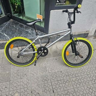 Bicicleta BMX plateada con ruedas verdes