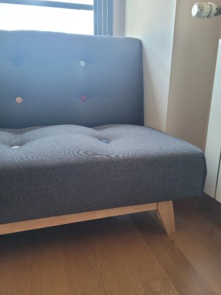 Sofá cama gris estilo capitoné.