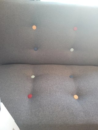 Sofá cama gris estilo capitoné.