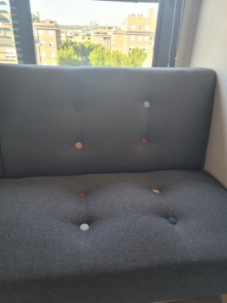 Sofá cama gris estilo capitoné.