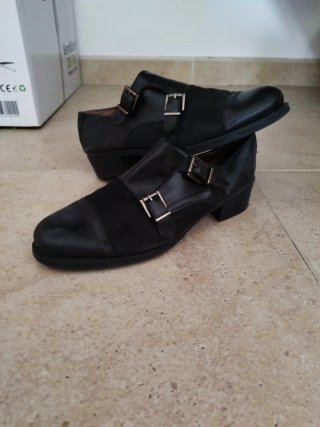 Zapatos negros de piel con doble hebilla.
