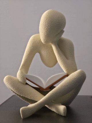 Statua uomo seduto legge libro