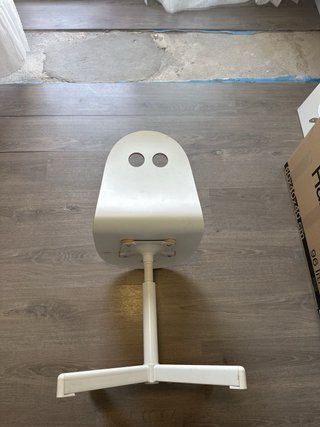Silla infantil blanca de altura regulable.
