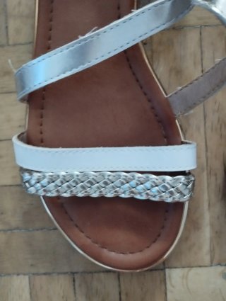 Sandalias planas plateadas y blancas de mujer.
