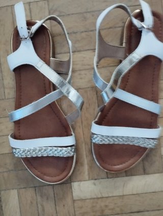 Sandalias planas plateadas y blancas de mujer.