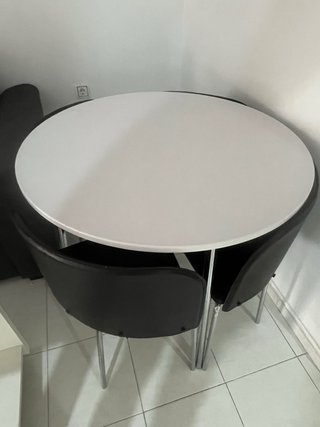 Mesa redonda blanca con 4 sillas negras