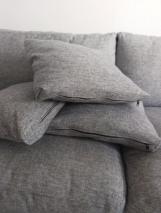 Sofá gris elegante con patas de acero.
