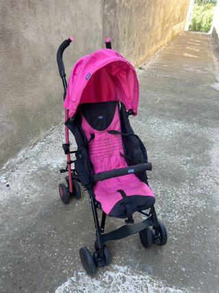Cochecito de bebé rosa con plástico de lluvia