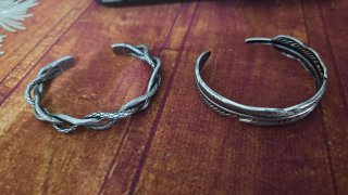 2 pulseras rígidas plateadas pluma y corona espina