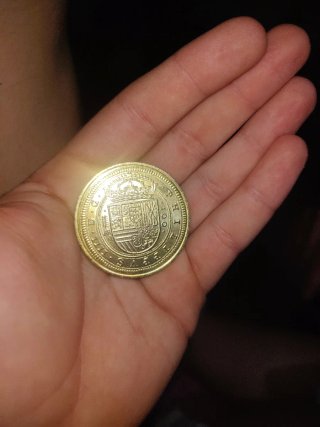 Moneda antigua dorada con diseño floral de oro