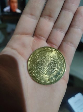 Moneda antigua dorada con diseño floral de oro