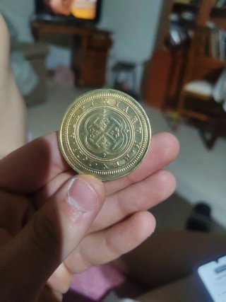 Moneda antigua dorada con diseño floral de oro