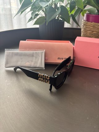 Gafas de sol Miu Miu montura negra y logo dorado