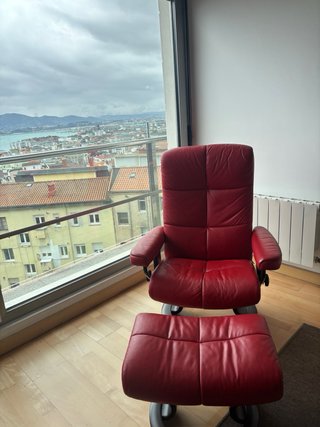 Sillón de piel rojo con reposapiés.