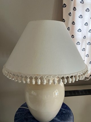 Lámpara cerámica beige con pantalla con borlas.