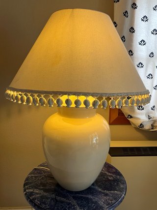 Lámpara cerámica beige con pantalla con borlas.
