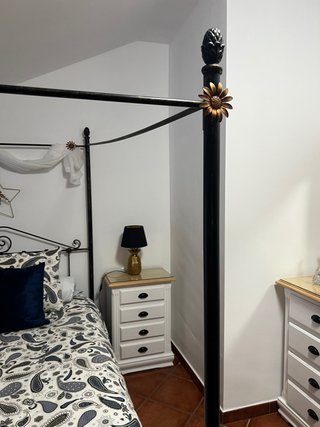 Elegante cama de matrimonio con dosel y muebles.