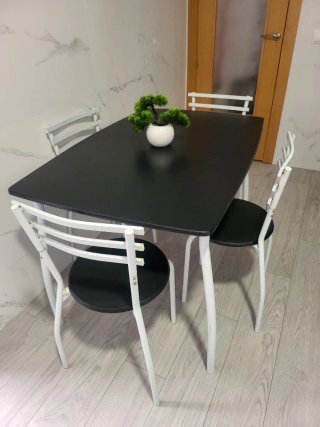 Mesa negra con 4 sillas blancas