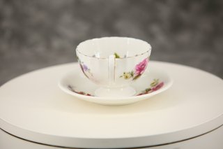Taza de té y plato de porcelana con rosas
