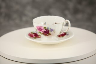 Taza de té y plato de porcelana con rosas