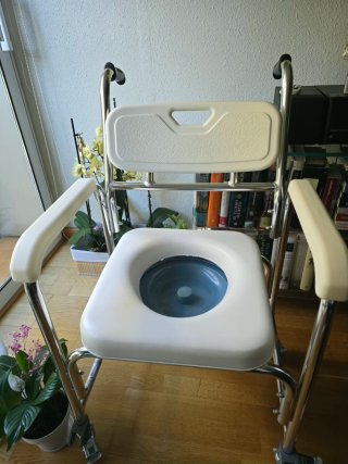 Silla de ducha con inodoro y ruedas para traslado.