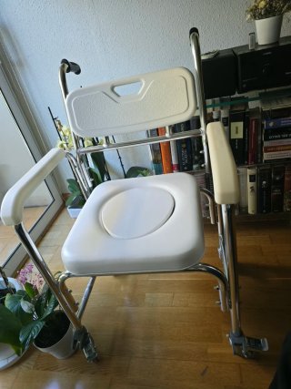 Silla de ducha con inodoro y ruedas para traslado.