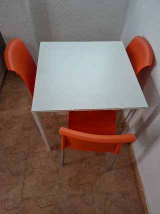 Mesa blanca con 3 sillas naranjas