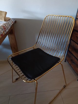 Silla metálica dorada con cojín negro