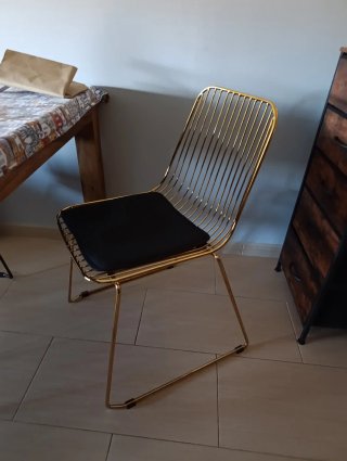 Silla metálica dorada con cojín negro