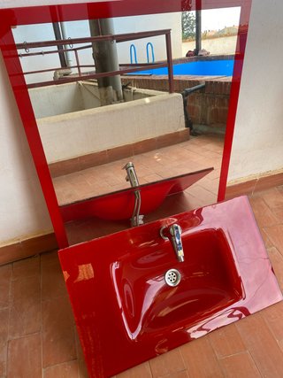 Lavabo y espejo baño rojo.