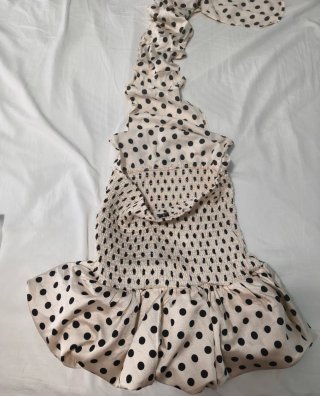 Vestido beige con lunares negros y lleva pantalón