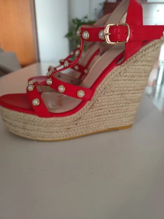 Sandalias rojas con alto tacón de esparto.
