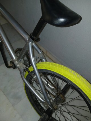 Bicicleta BMX plateada con ruedas amarillas