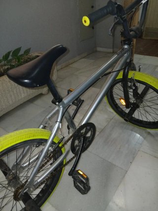 Bicicleta BMX plateada con ruedas amarillas