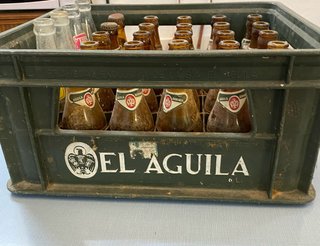 Vecchia scatola di birra El Águila con bottiglie