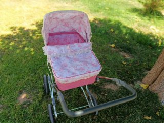 Carro de muñecas rosa con capota floral