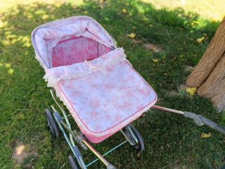 Carro de muñecas rosa con capota floral