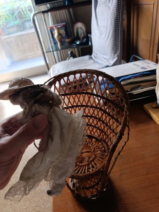 Muñeca de porcelana con sillón de mimbre