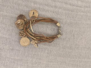 Pulsera con dijes dorados y cordón marrón