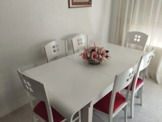 Mesa blanca con 6 sillas y cojines rojos