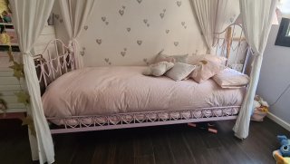 Cama juvenil rosa con dosel.