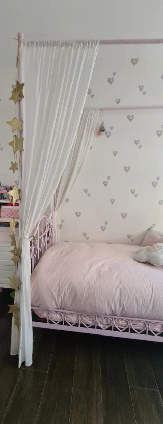 Cama juvenil rosa con dosel.