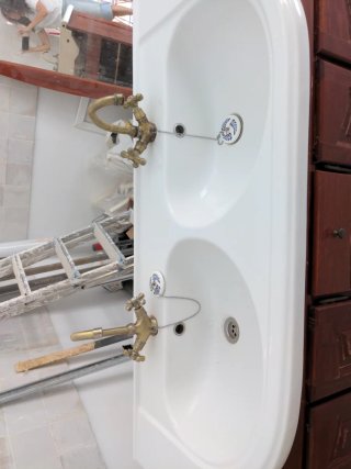 Mueble de baño con lavabo doble y grifos.