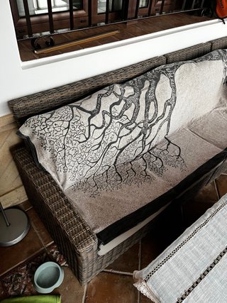 Sofá de ratán esquinero, con mesa de cristal.