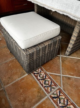 Sofá de ratán esquinero, con mesa de cristal.