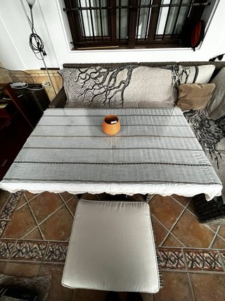 Sofá de ratán esquinero, con mesa de cristal.