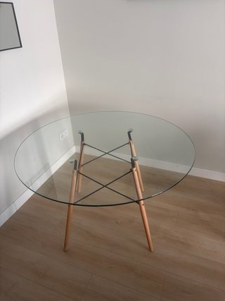 Mesa redonda de cristal con patas de madera.
