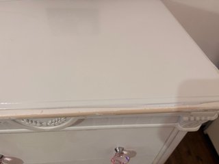 Cómoda y mesita blancas con tiradores de cristal.