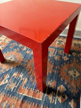 Mesa cuadrada roja con desperfectos