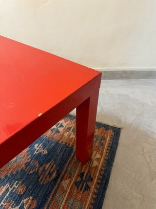 Mesa cuadrada roja con desperfectos
